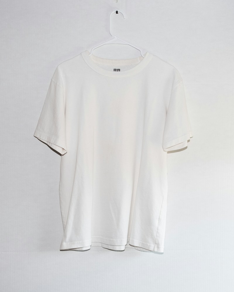 Unbranded white tee hanging on pale background